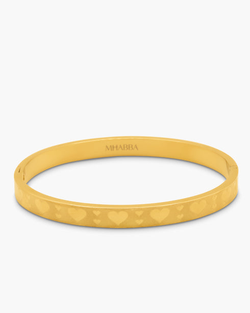 gold bangle with heart pattern on a white background