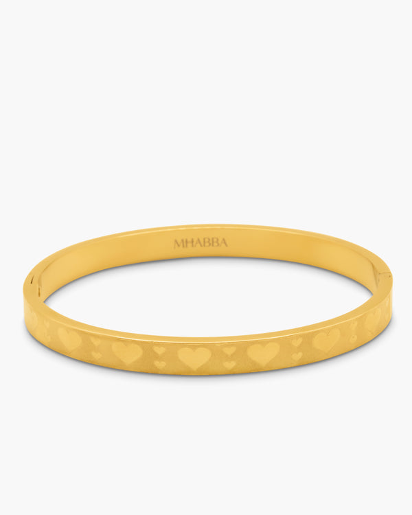 gold bangle with heart pattern on a white background
