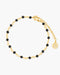 Gold anklet with black beads on a white background