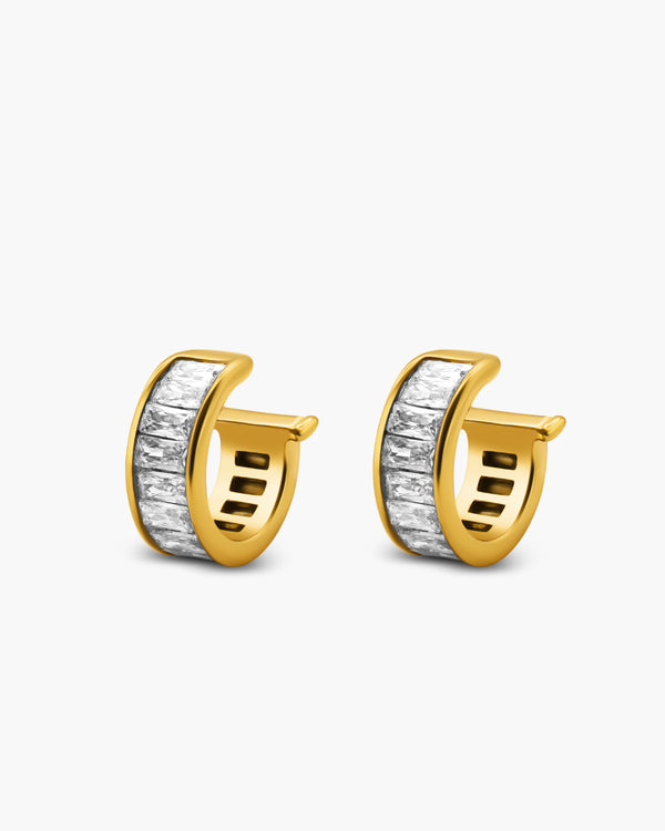 Gold hoop earrings with a white stone on a light gray background