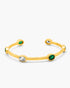 Gold bangle with green and clear gemstones on a white background