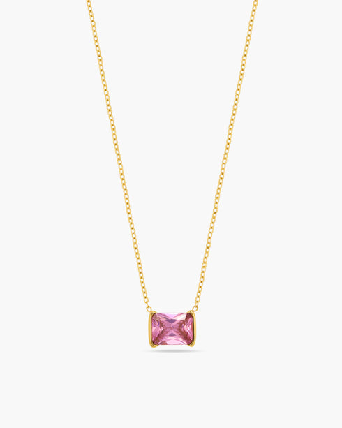 Gold necklace with a pink gemstone on a white background