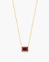 Gold necklace with a red gemstone pendant on a white background