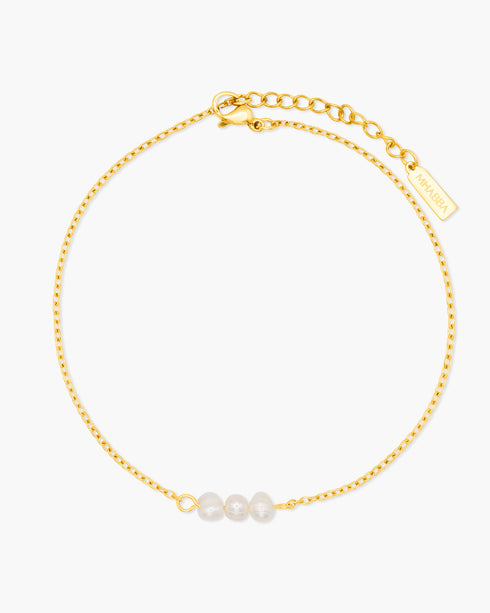 Gold anklet with three pearls on a white background