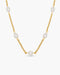 Gold chain necklace with white pearls on a white background