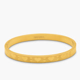 gold bangle with heart pattern on a white background