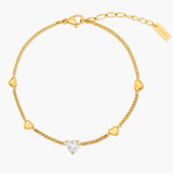 Gold bracelet with heart-shaped diamond on a white background