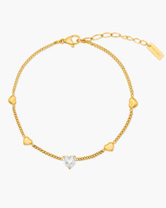 Gold bracelet with heart-shaped diamond on a white background