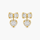 Gold bow-shaped earrings with heart details on a white background