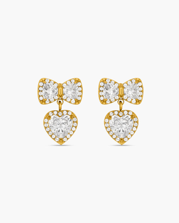 Gold bow-shaped earrings with heart details on a white background