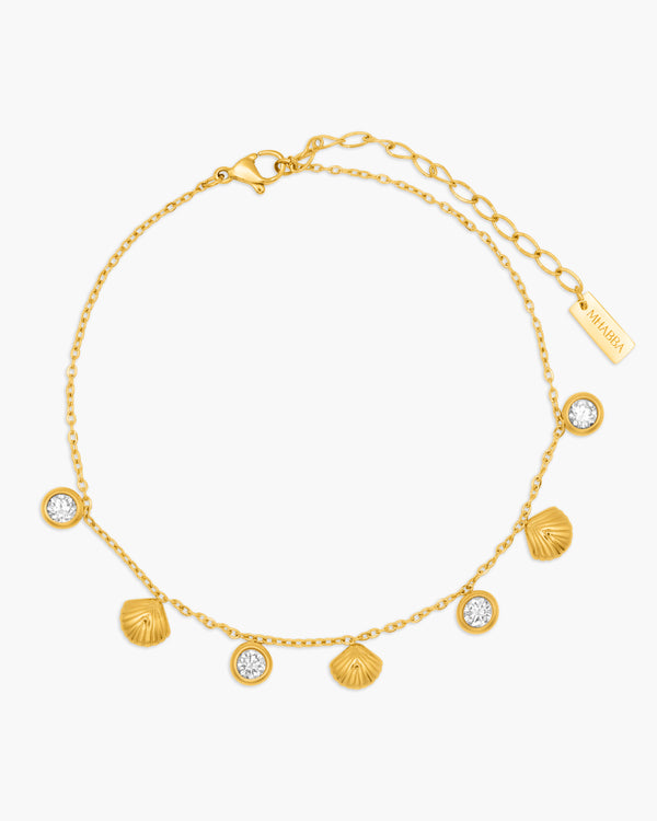 Gold anklet with shell and gemstone charms on a white background