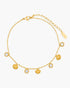 Gold anklet with shell and gemstone charms on a white background