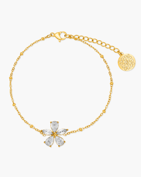 Gold bracelet with a floral clasp on a white background