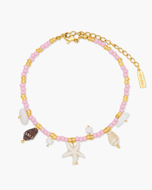 Anklet with pink beads, gold accents, and starfish charm on a white background