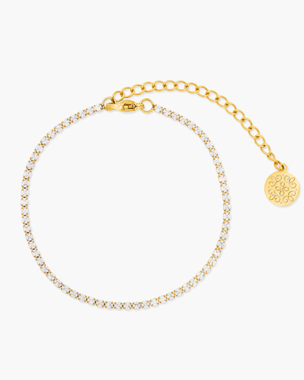 Gold bracelet with a round charm on a white background