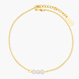 Gold anklet with three pearls on a white background