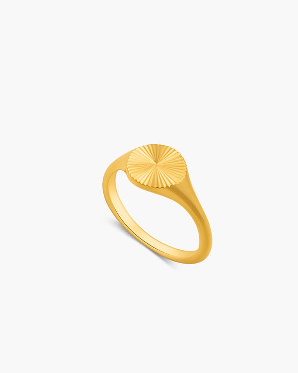Gold ring with a sunburst design on a white background