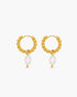 Gold hoop earrings with pearl drops on a white background