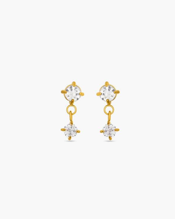 Gold earrings with clear gemstones on a white background