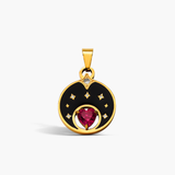 Gold pendant with a red gemstone and black enamel design on a white background